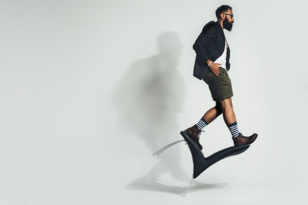 Un hombre con look hípster hace equilibrio sobre una silla