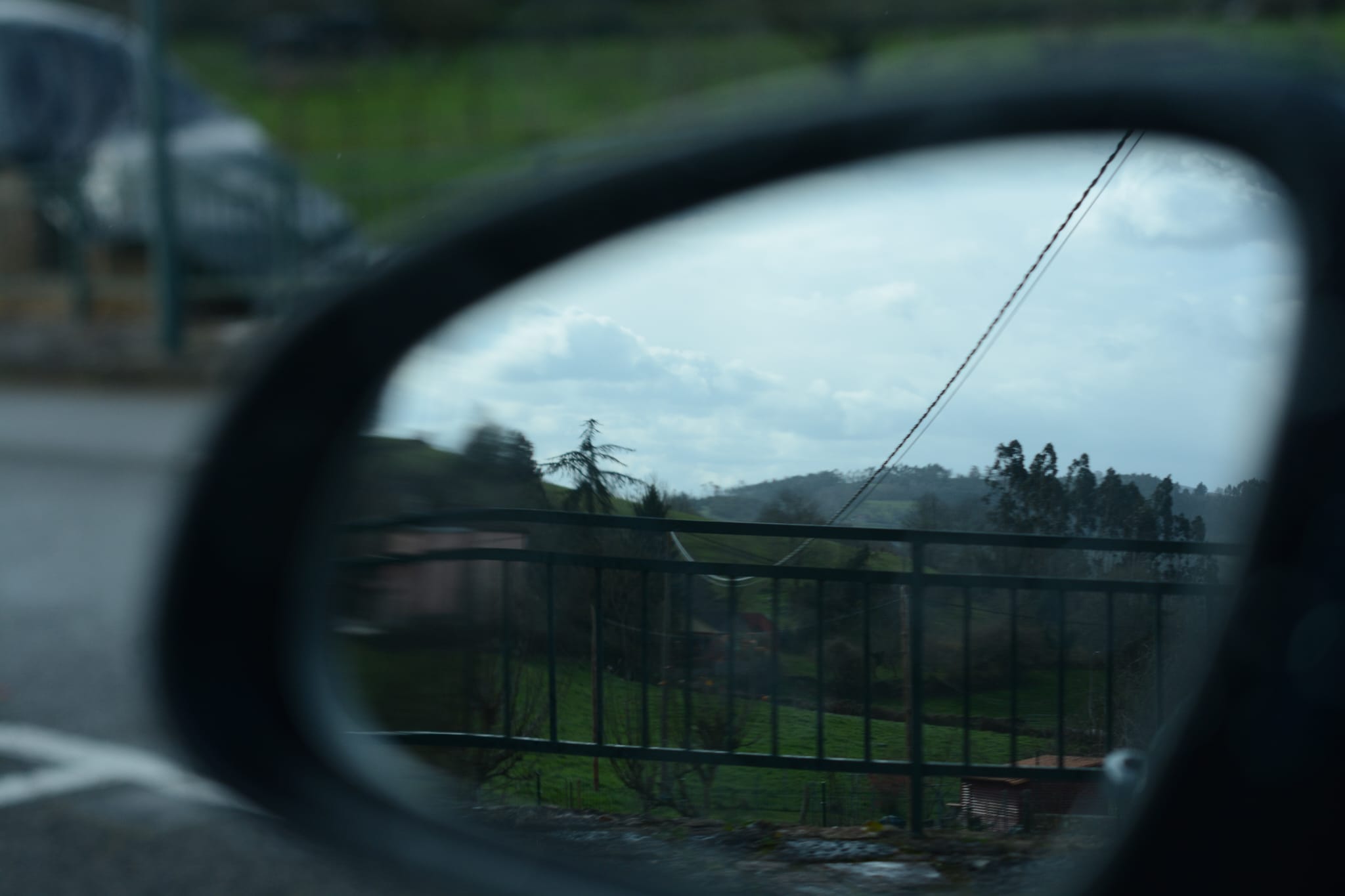 El espejo retrovisor de un coche que avanza muestra el paisaje rural que queda atrás